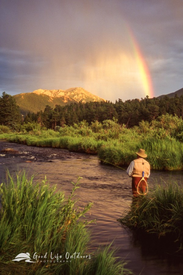 A lone fly angler standing in the Big Thompson River in front of a brilliant rainbow in Morraine Park within Colorado's Rocky Mountain National Park.