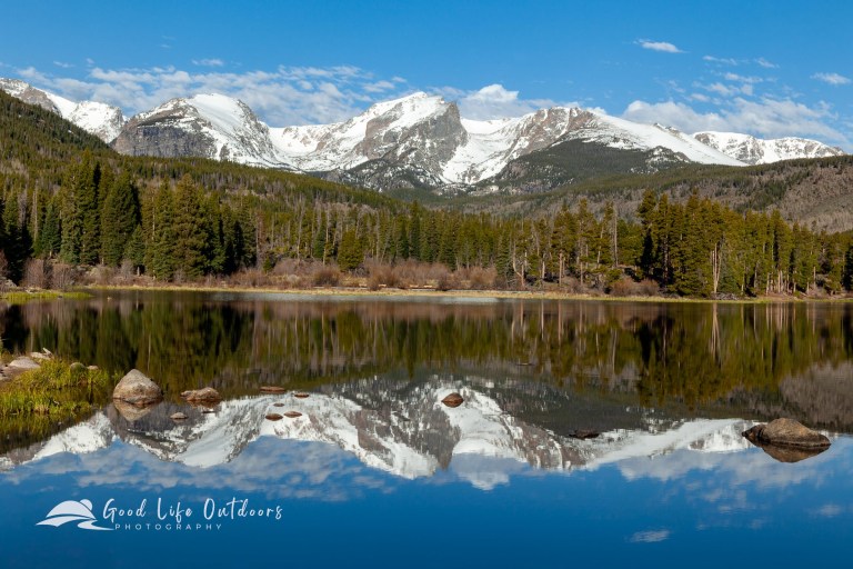 Spruce Lake in Rocky Mountain National Park reflects Hallet Peak in the center, Tyndall Glacier and Flattop Mountain on the right, and Otis Peak on the left during a calm spring morning.