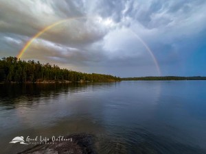 A full rainbow reflecting on the lake.